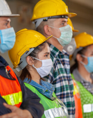 Workers wear protective face masks for safety in machine industrial factory.